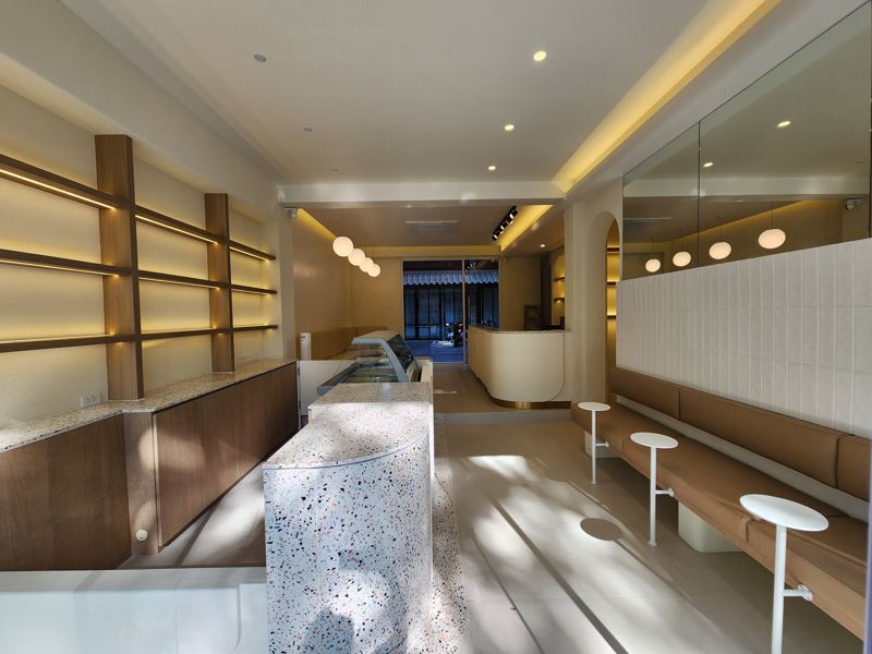 ร้านชานม ผนังชั้นวางไฟซ่อน เคาน์เตอร์หินขัดและม้านั่งยาว